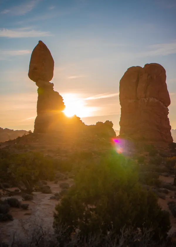 Balanced Rock in Arches National Park silhouetted against the setting sun.