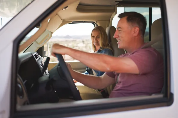 Smiling couple in the cab of an RV, the man at the wheel