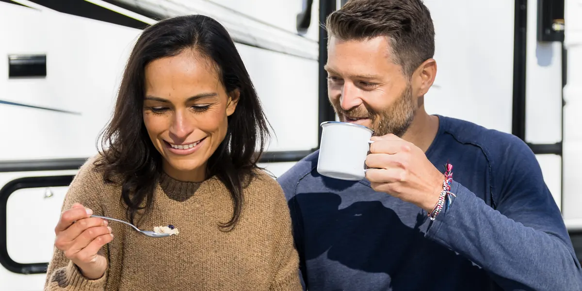 Couple having breakfast at a table beside the door of their RV