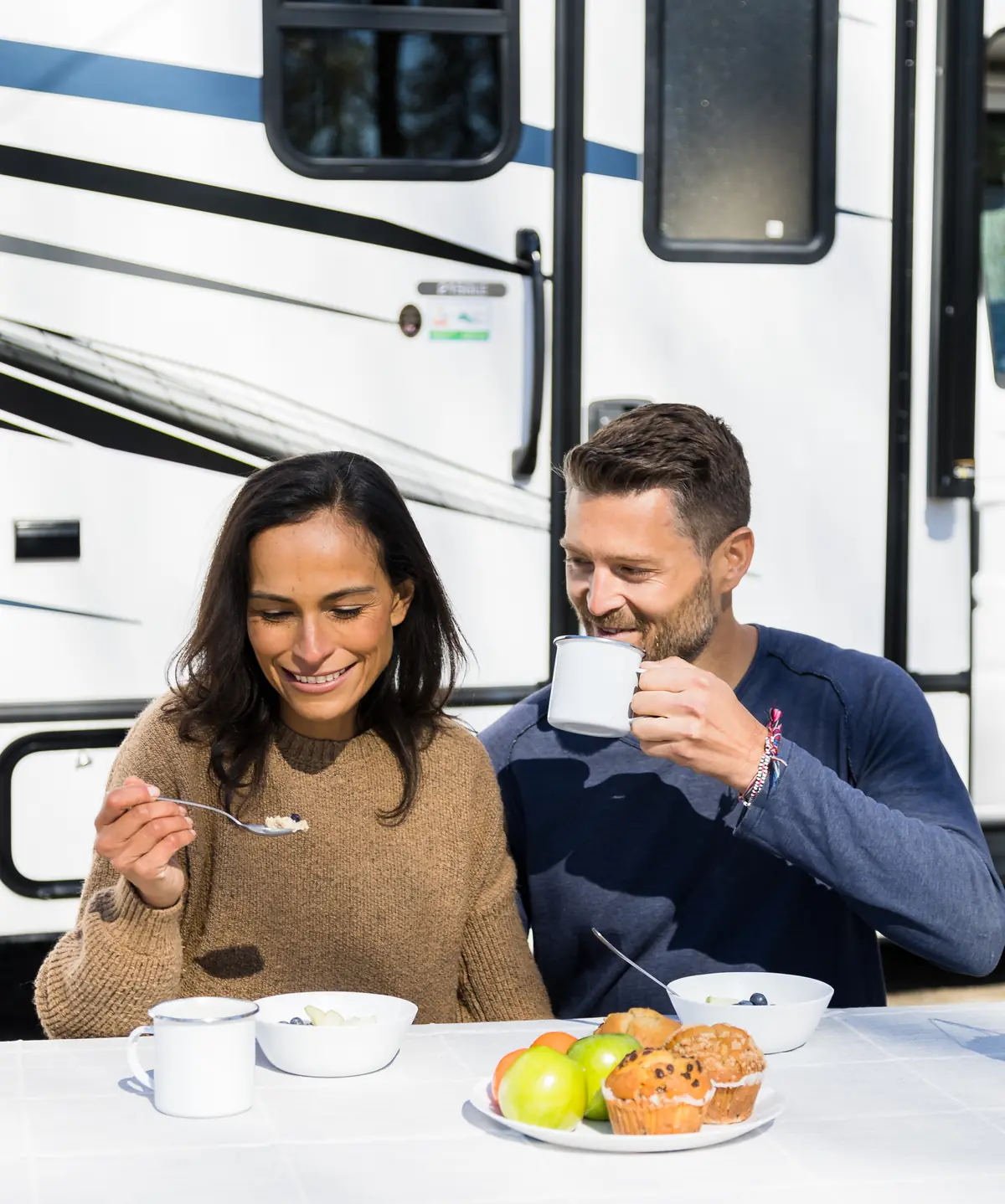 Couple having breakfast at a table beside the door of their RV