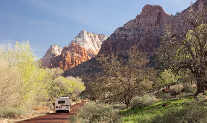 RV on the red-paved scenic drive in Zion, below towering canyon walls