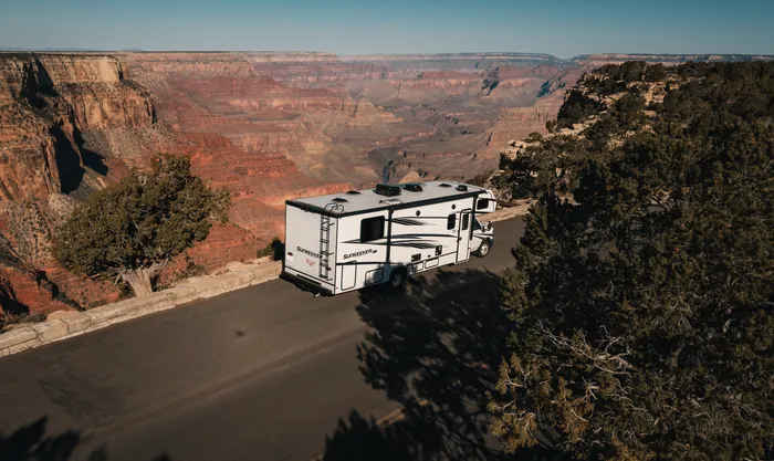 Aerial view of an RV on the rim road above the Grand Canyon at golden hour