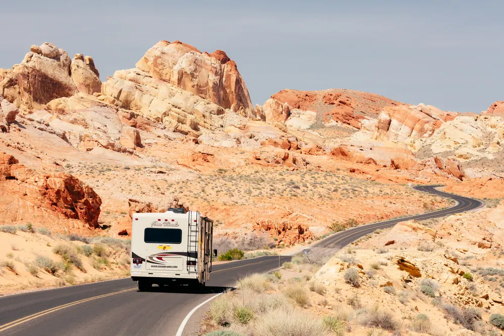 RV on a winding road through red and cream sandstone formations