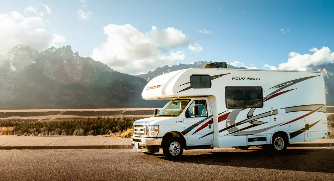 RV in front of jagged mountain peaks under a cloudy sky
